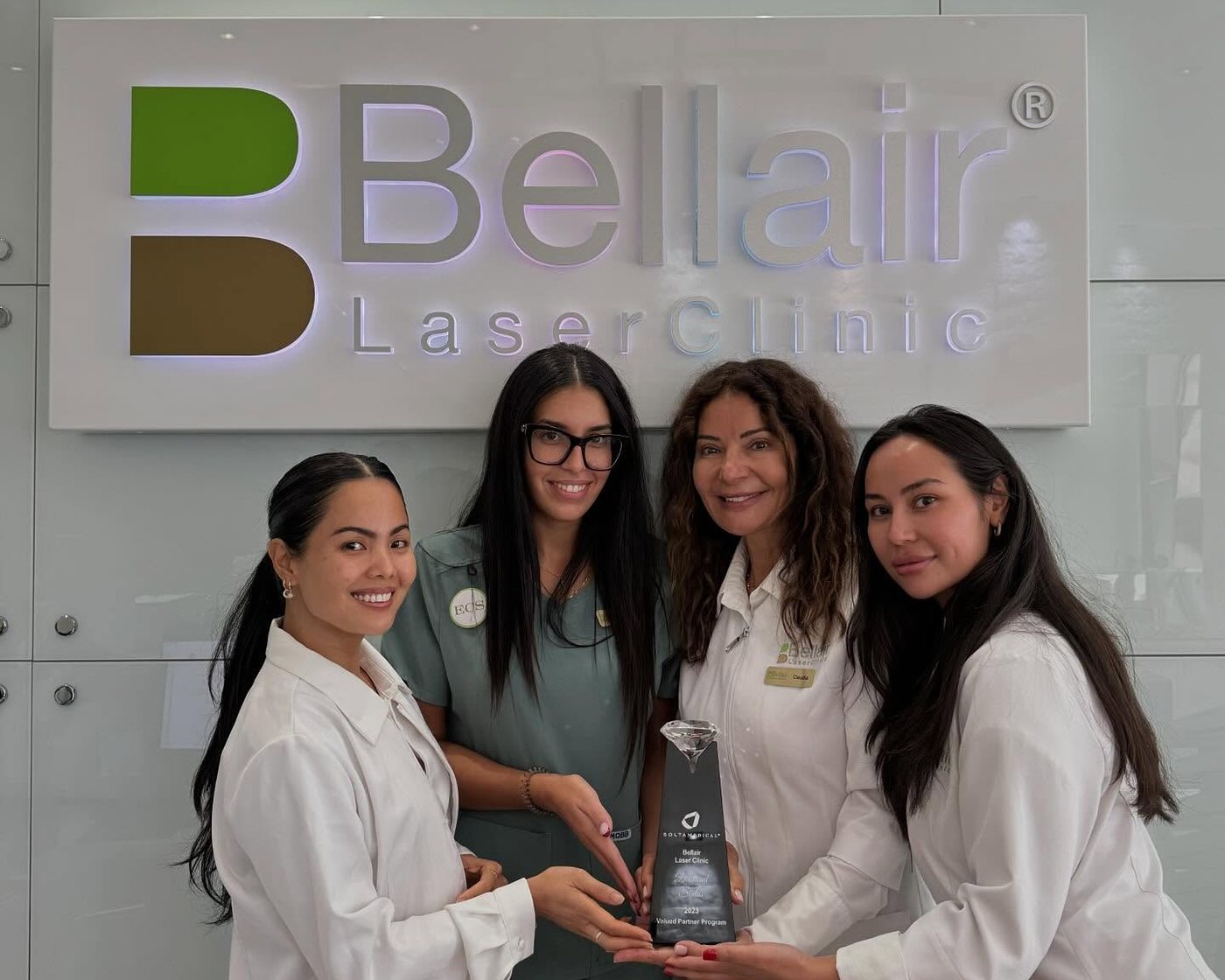 Four members of the Bellair team holding the Solta Medical Valued Partner award in front of the Bellair Laser Clinic sign